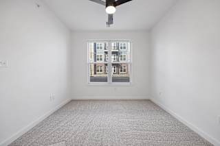 A room with a carpeted floor and a window showing a building outside.