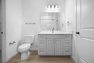 A white bathroom with a toilet, sink, and mirror.