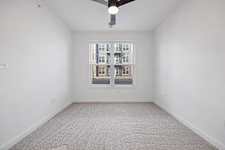 A room with a carpeted floor and a window showing a building outside.