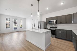 A modern kitchen with a white island and dark brown cabinets.