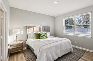 A bedroom with a large bed and a window with blinds.