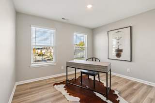 A room with a table and a cowhide rug in front of a window.