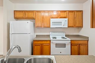 A kitchen with white appliances and wooden cabinets.