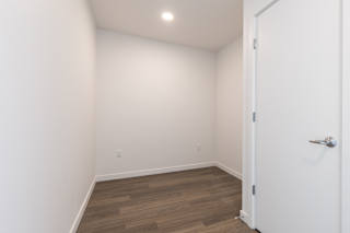 A room with a white door and wooden flooring.