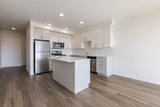 A modern kitchen with a refrigerator, microwave, and oven.