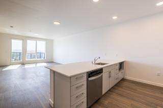 A kitchen with a sink, stove, and drawers.