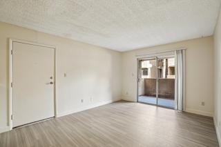 A room with a white door and a sliding glass door leading to a balcony.