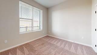 A room with a carpeted floor and a window with blinds.