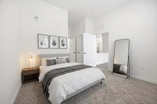 A bedroom with a bed, nightstand, and a mirror.