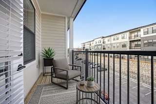 A balcony with a chair, table, and potted plant.