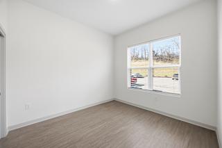 A room with a window showing a view of a parking lot.