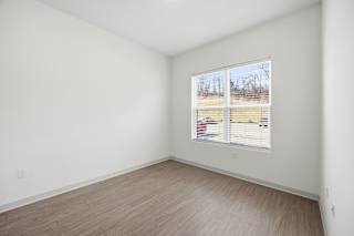 A room with a window showing a view of a field.