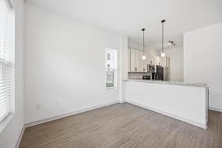 A spacious, empty room with a kitchenette in the background.