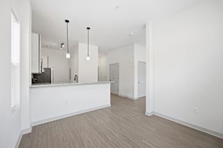 A white kitchen with wood flooring and a bar area.