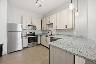 A kitchen with a granite counter top and stainless steel appliances.