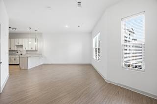 A spacious room with wooden flooring and white walls.