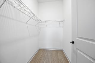 A white closet with a door and shelves.