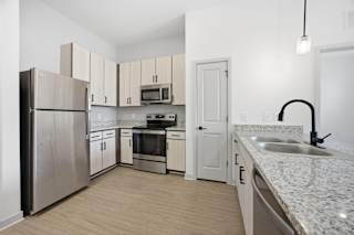 A kitchen with a refrigerator, oven, sink, and cabinets.
