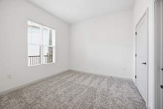 A room with a carpeted floor and a window with blinds.