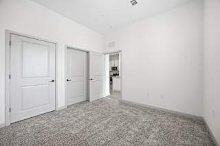 A room with three doors and a carpeted floor.