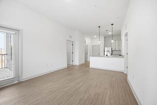 A spacious room with wooden flooring and white walls.