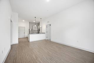 A large empty room with wooden flooring and white walls.