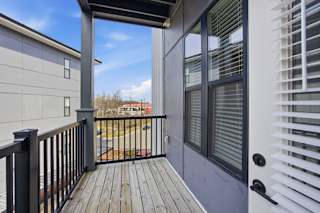 A balcony with a black railing and a grey wall.