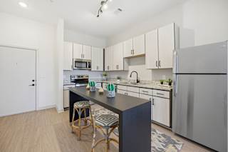 A kitchen with white cabinets and a black island.