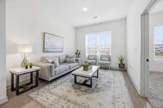 A living room with a grey couch, a coffee table, and a painting on the wall.