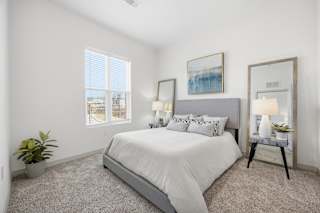 A bedroom with a large bed, a potted plant, and a painting on the wall.