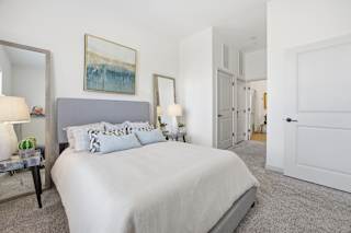 A bedroom with a large bed and a painting on the wall.