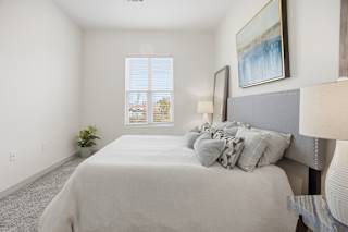 A bedroom with a large bed and a painting on the wall.