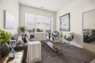 A living room with a grey couch, a coffee table, and a large window.