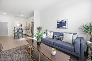 A living room with a blue couch and a painting on the wall.