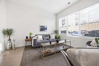 A living room with a grey couch, a coffee table, and a large window.