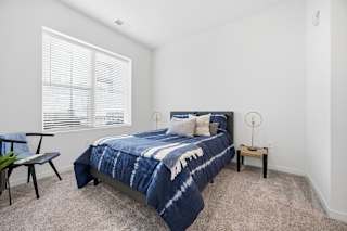 A bedroom with a bed, a chair, and a small table.