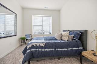 A bedroom with a bed, a chair, and a window.