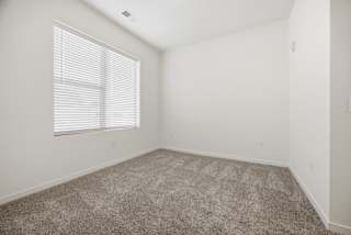 A room with a carpeted floor and a window with blinds.