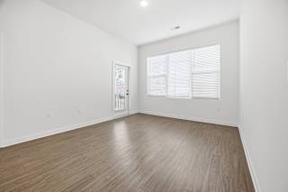 A room with wooden flooring and a window with blinds.