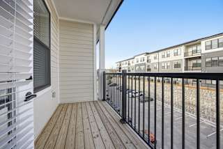 A balcony with a black railing and wooden floor.