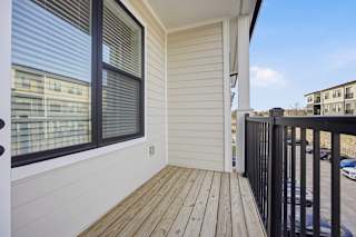 A balcony with a black railing and wooden floor.
