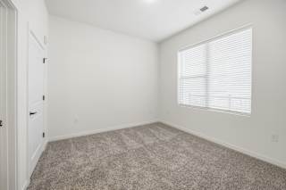 A room with a carpeted floor and a window with blinds.