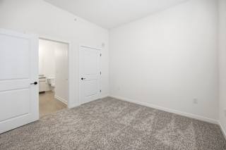 A room with a carpeted floor and two doors.