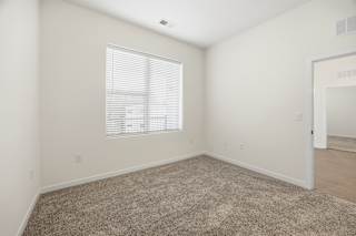 A room with a carpeted floor and a window with blinds.