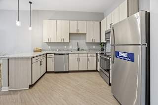 A kitchen with a stainless steel refrigerator and wooden flooring.