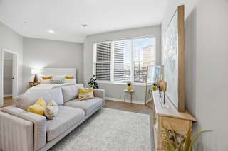 A living room with a grey couch and yellow pillows.