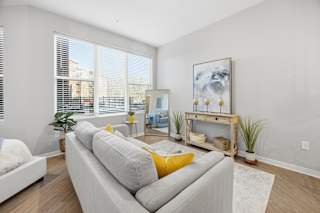 A living room with a grey couch and a painting on the wall.