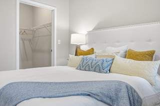 A bed with a blue blanket and pillows in a white room.