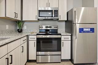 A modern kitchen with a stainless steel refrigerator that has a blue sticker on it.