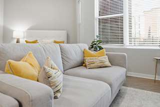 A grey couch with yellow pillows in a living room.